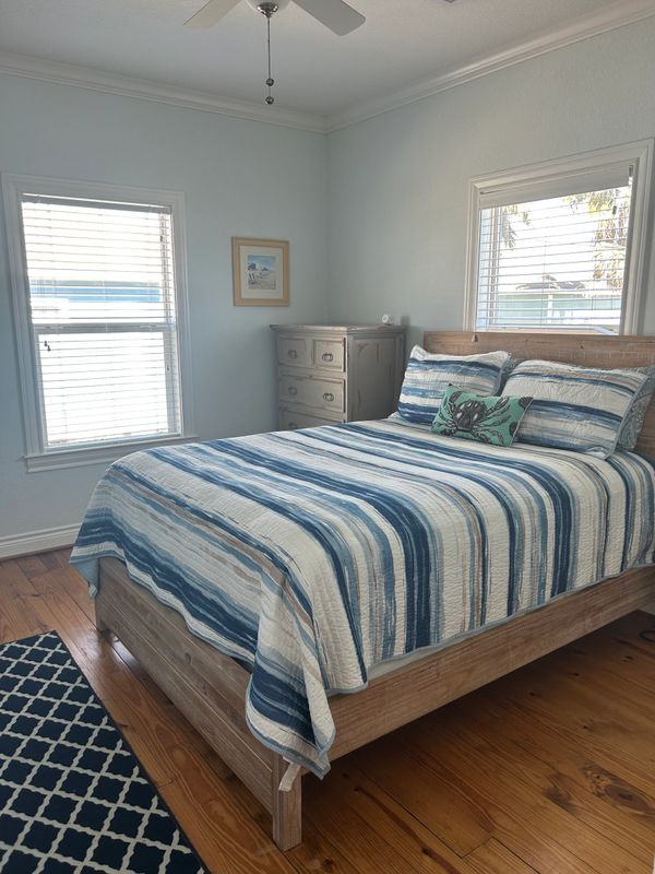Cozy bedroom with blue-striped bedding and wooden furniture.