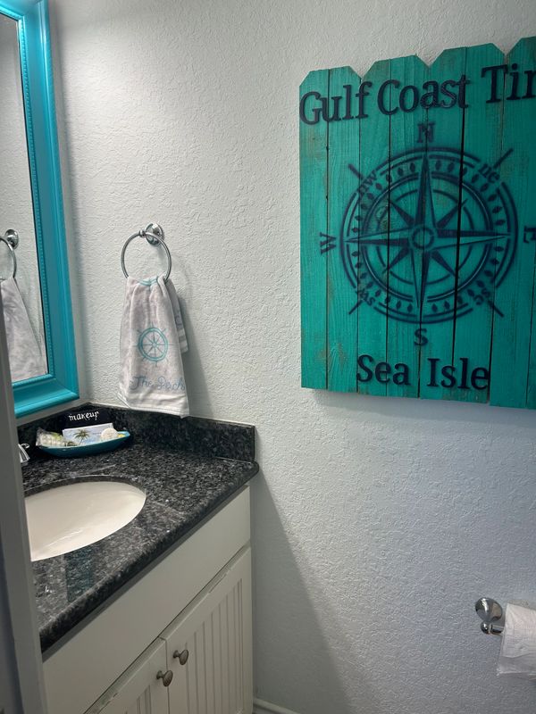 Coastal-themed bathroom with turquoise accents and a compass wall art.