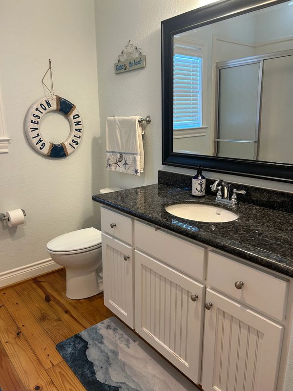 Coastal-themed bathroom with wooden floor and granite countertop.