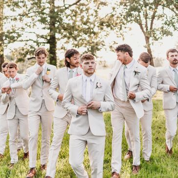 Group of groomsmen in beige suits outdoors.