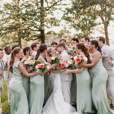 Bridal party celebrating outdoors with flowers.