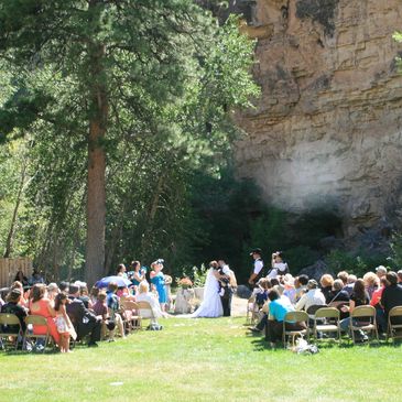 Outdoor wedding ceremony in a natural setting with guests seated.