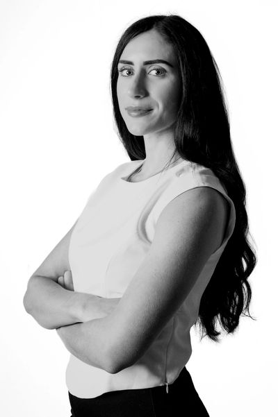 Confident woman with long hair posing with arms crossed in black and white.