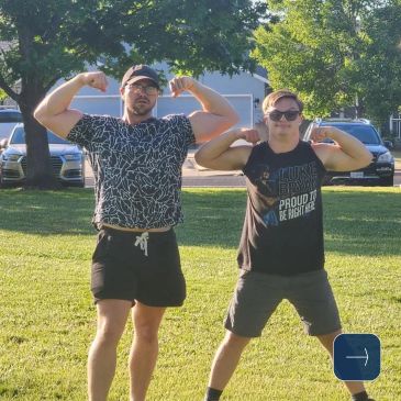 Two men flexing their muscles outdoors in a sunny park.