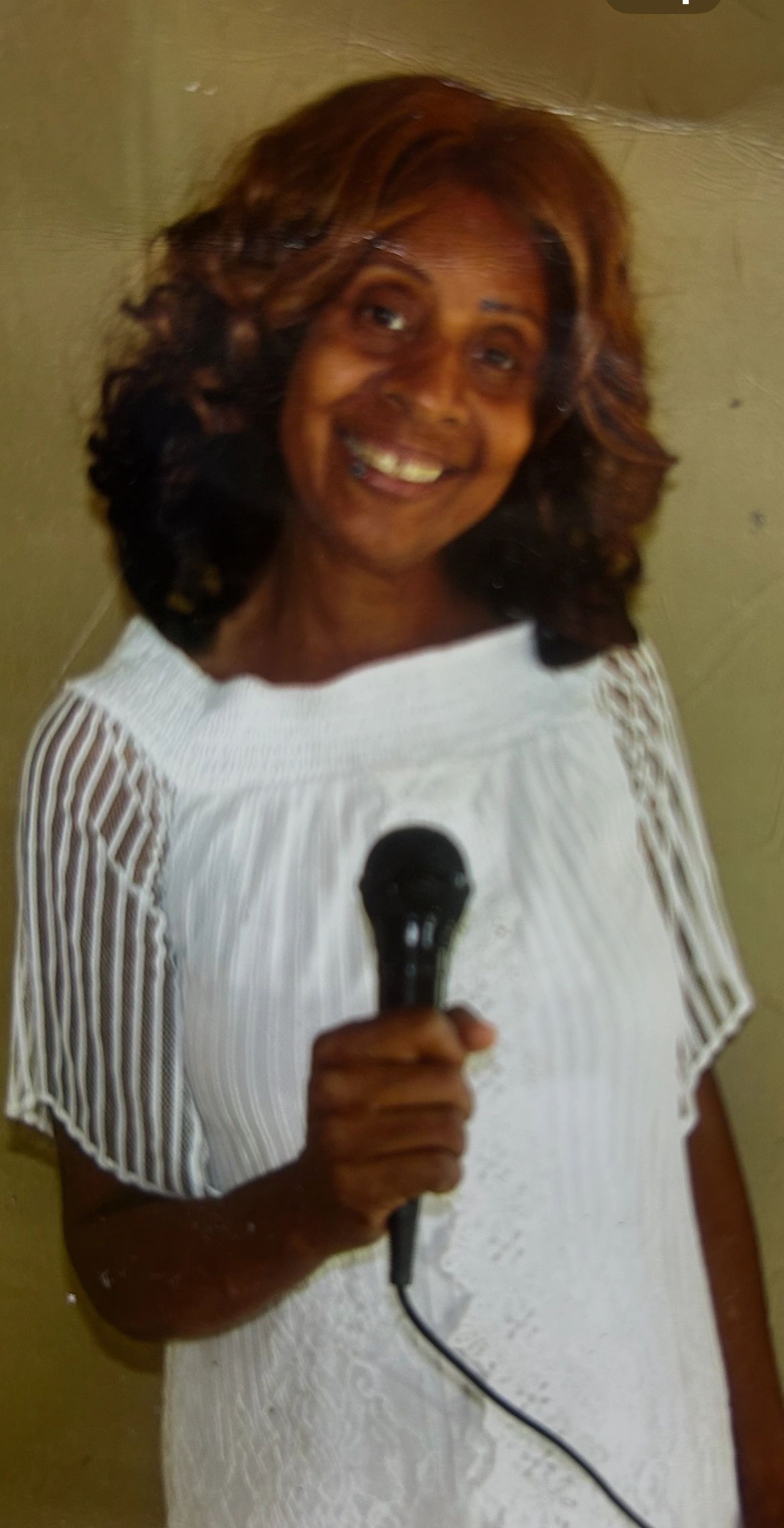 Woman smiling while holding a microphone.