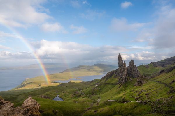 Rainbow over the Old Man of Storr, a rocky landscape with green hills and water