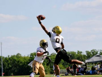 Football player leaps to catch a pass during a game.
