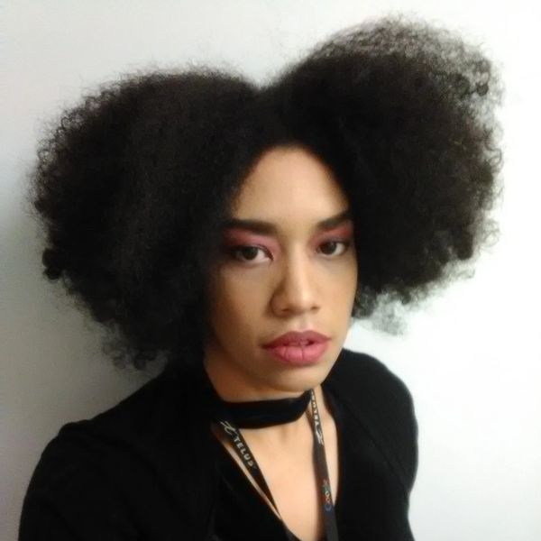 Person with voluminous natural curly hair and makeup.