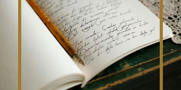 Open notebook with cursive writing and a pen.
