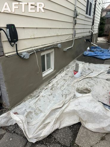 Freshly repaired and painted house foundation with work tools around.