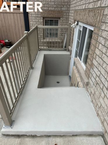 Newly renovated basement entrance with smooth concrete finish and metal railing.