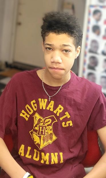 Young person wearing a Hogwarts Alumni shirt.