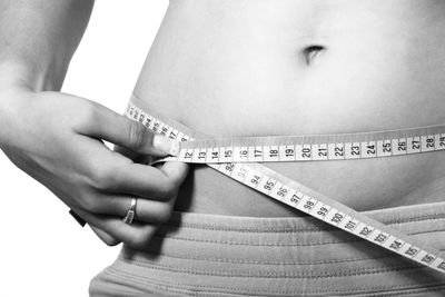 Person measuring waist with a tape measure.