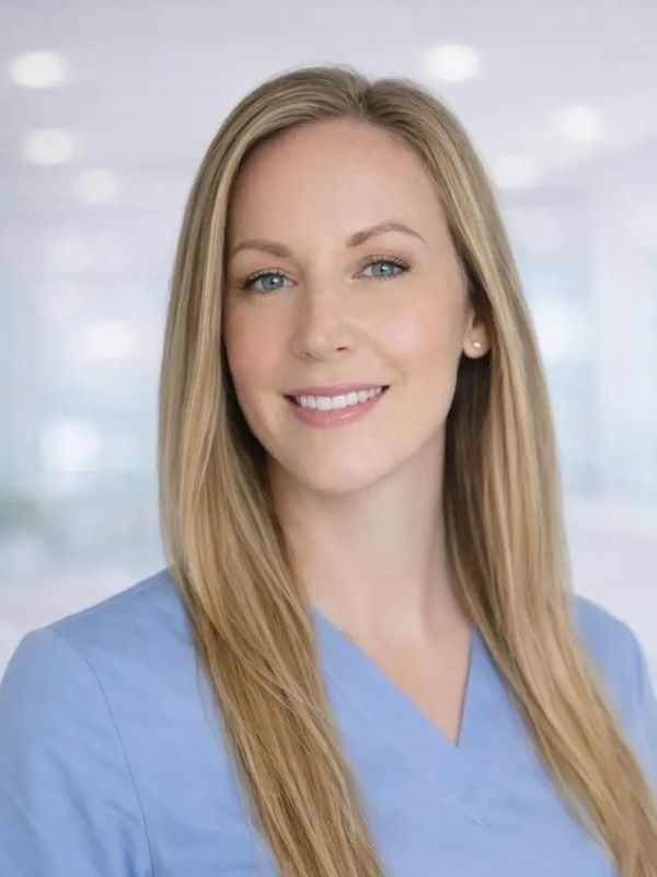 Smiling woman with long blonde hair wearing a blue medical scrub top.