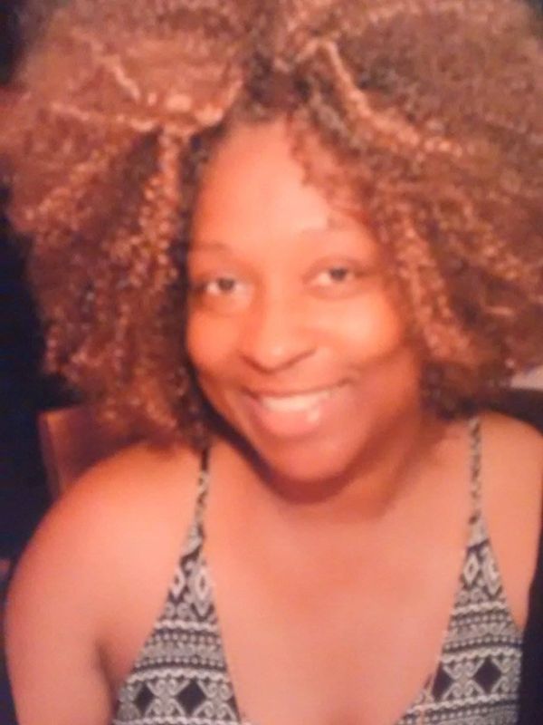 Smiling woman with voluminous curly hair and patterned top.
