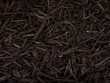 Close-up of dark brown wood mulch in a garden bed.