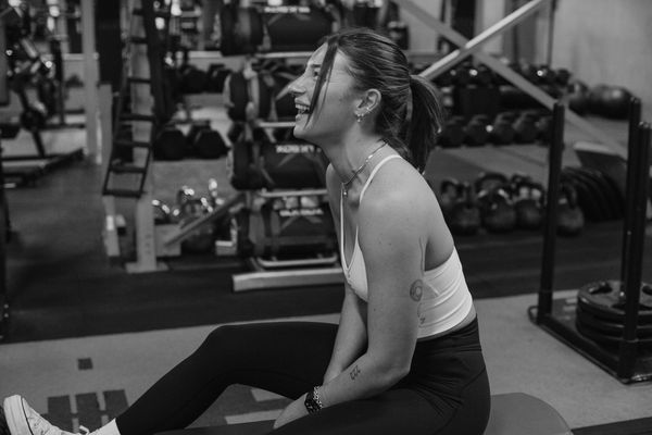 Smiling personal trainer/ online coach, in workout attire training in Fusion 3 Fitness gym.