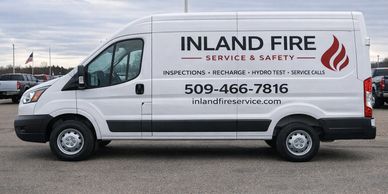 A white service van for Inland Fire with contact details and fire safety services listed.