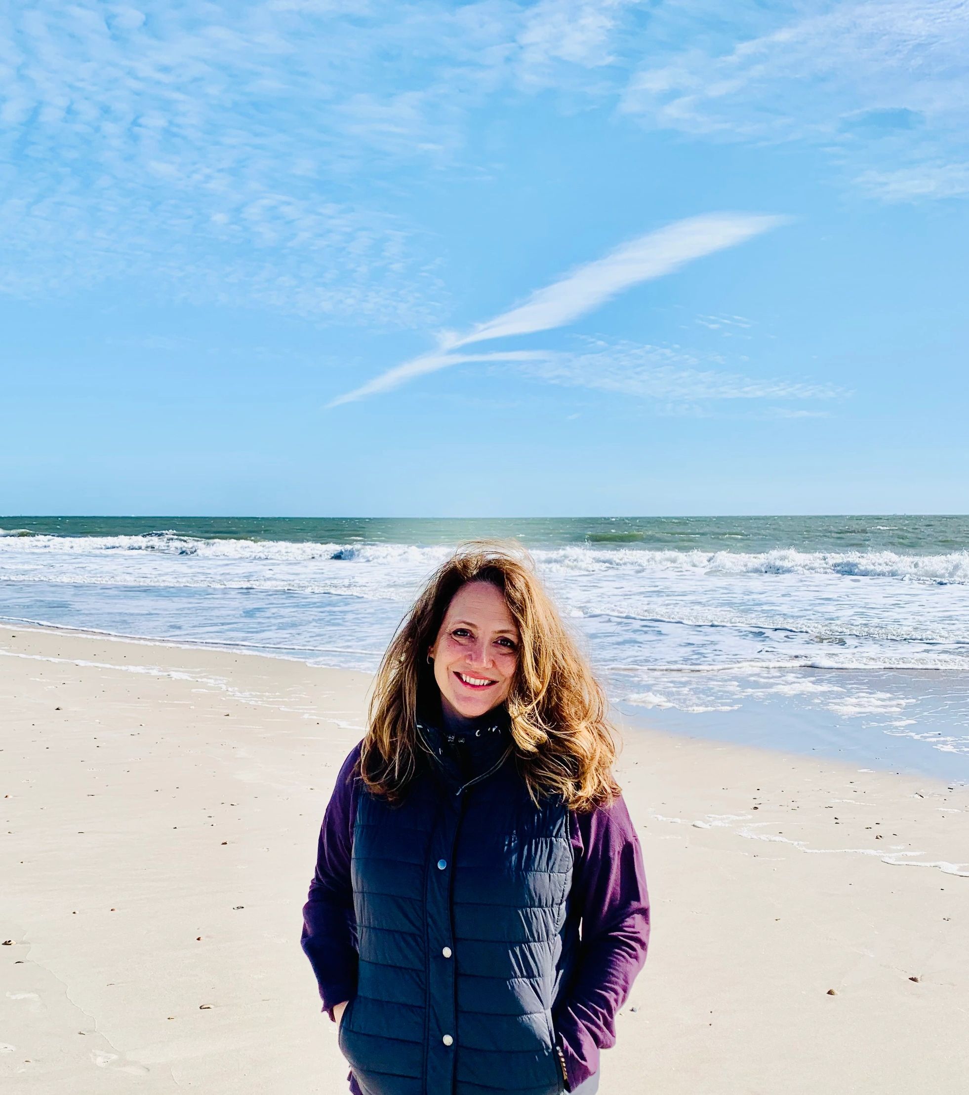 A person wearing a jacket and standing near the beach