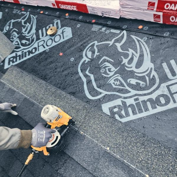 Person installing RhinoRoof waterproofing membrane on a roof.