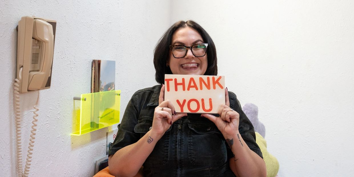 Woman smiling and holding a thank you sign.