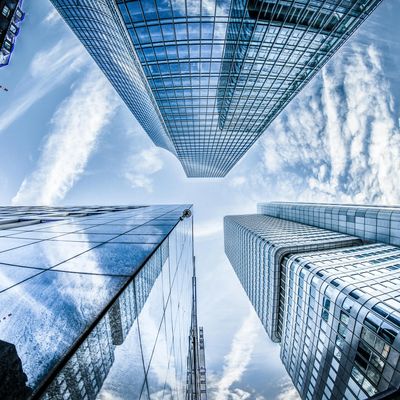 Looking up at towering modern skyscrapers under a blue sky with clouds.