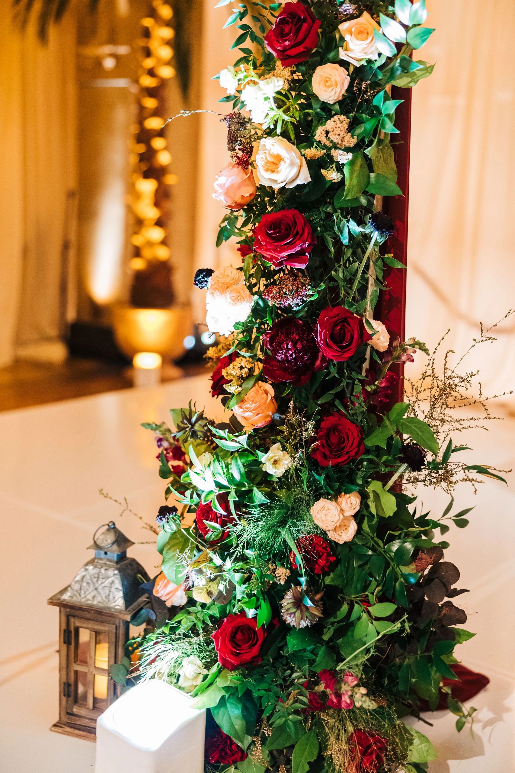 A vibrant floral arrangement with red, white, and peach roses and green leaves.