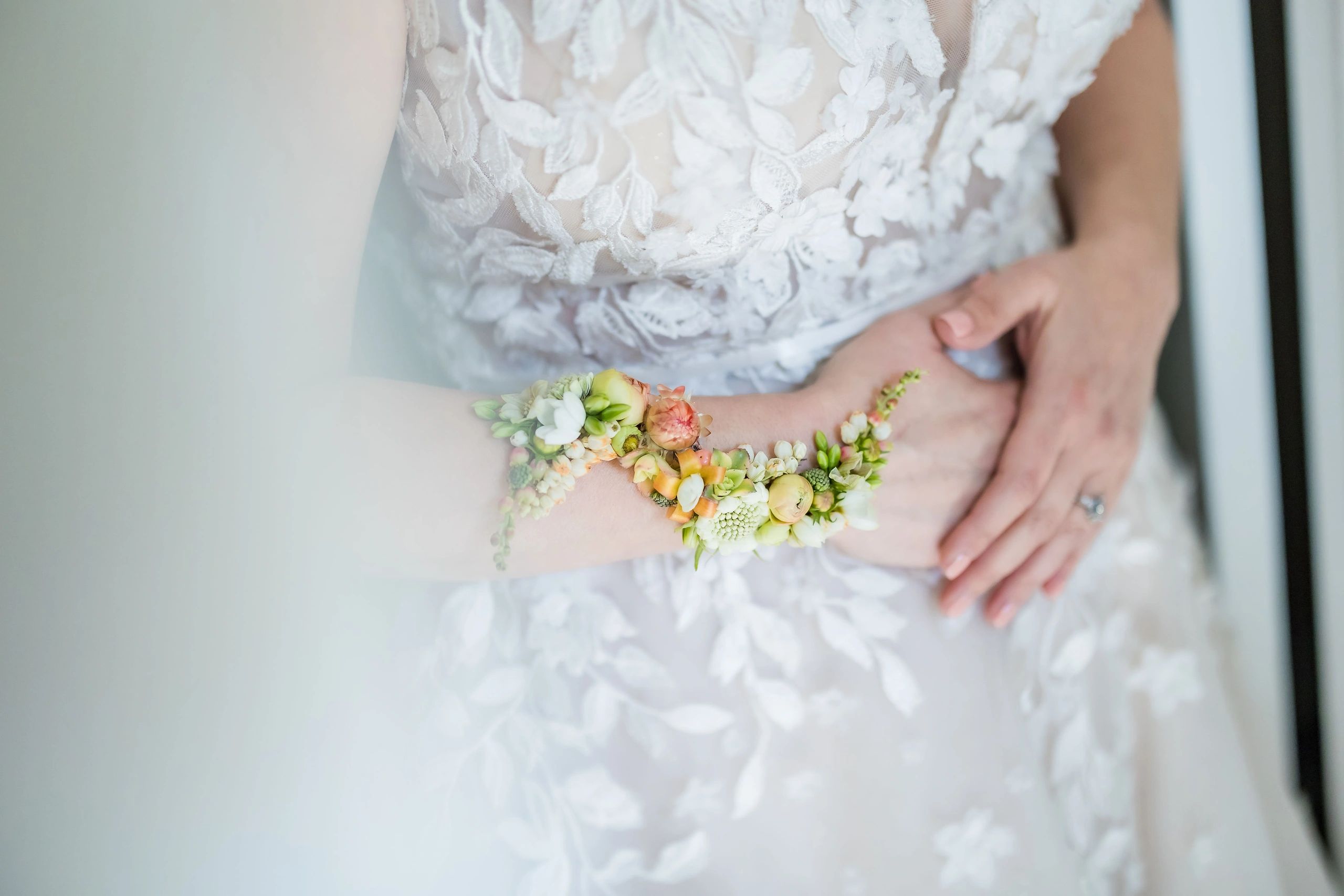 Bride in lace dress with delicate floral wrist corsage.