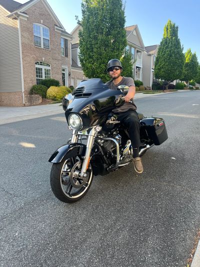 Man riding a black motorcycle in a residential area.
