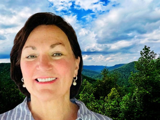 Close-up of a smiling woman with a Fall Creek Falls park scenic overlook in the background