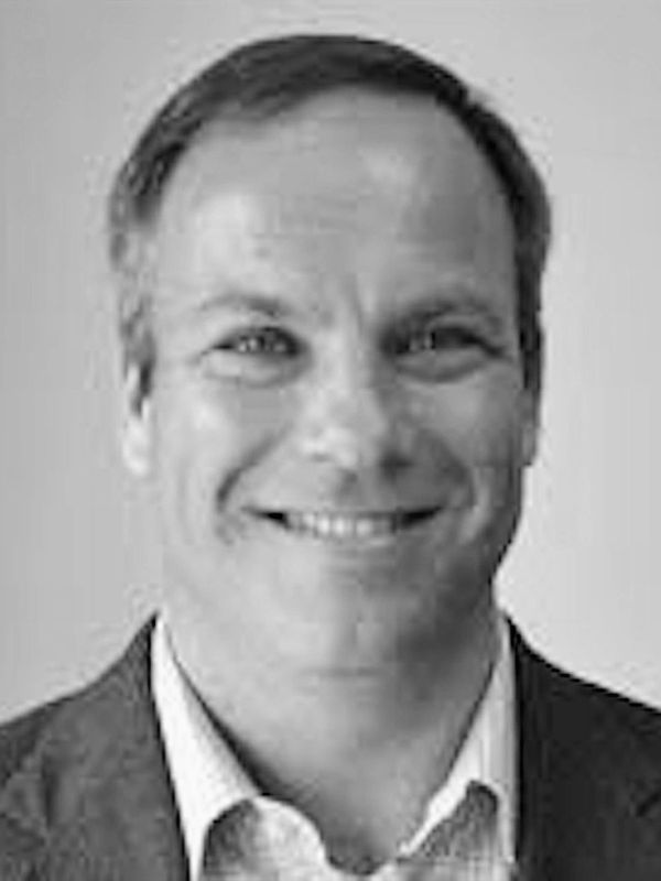 Black and white headshot of a smiling man.