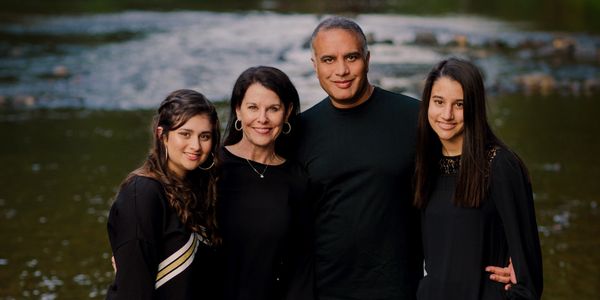 A family posing for a picture in front of a river.