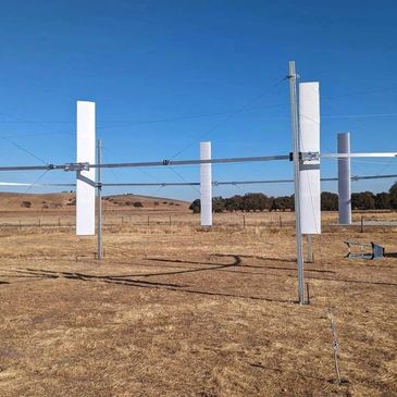Tall white vertical panels on a metal frame in a dry field under a clear blue sky.
