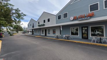 Exterior view of a small shopping plaza with restaurants and seating.