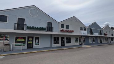 A row of shops in a small shopping plaza on a cloudy day.