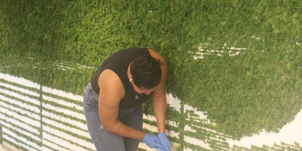 Person kneeling on grass wearing gloves.