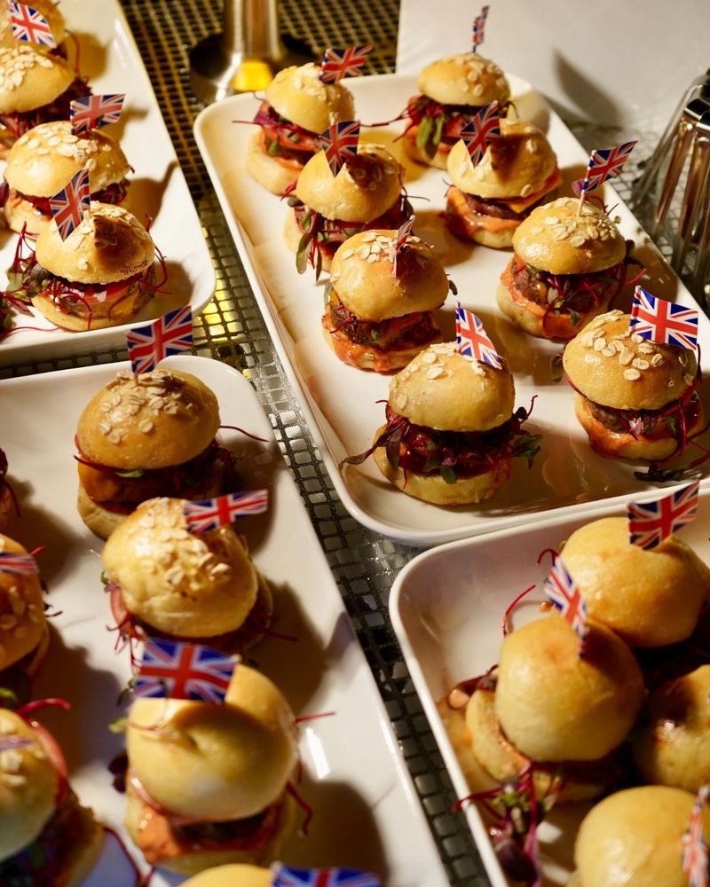 Mini burgers with oat-topped buns and British flags on toothpicks.