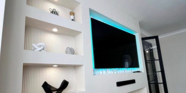 Modern living room TV setup with built-in shelves and LED backlighting.