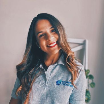 Woman with long hair smiling with a polo shirt showing Behavior Evolution logo