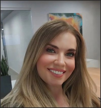 Smiling woman with long blonde hair in a modern office.