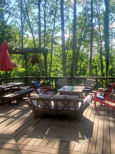 A cozy wooden deck patio with outdoor furniture surrounded by tall trees.