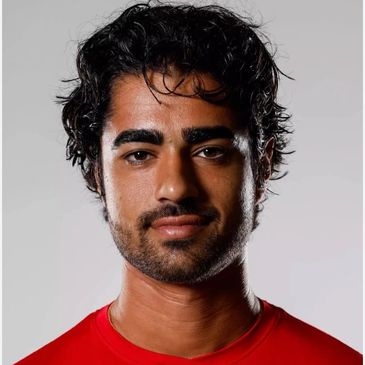Portrait of a man with curly hair and a red shirt.