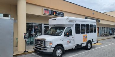White shuttle bus parked outside a thrift and pawn store.
