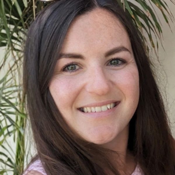 Emily Rogers, smiling with long dark hair and sunglasses on her head.