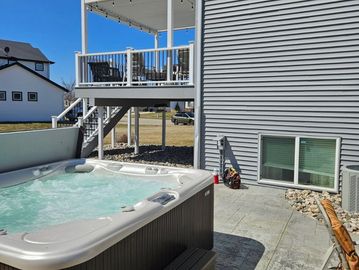Outdoor hot tub next to a modern house on a sunny day.