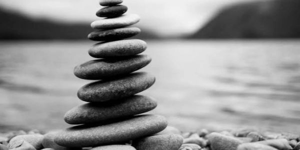 Stack of balanced stones by a lake in black and white.