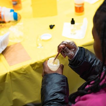 Person mixing a substance in a cup with a stick.