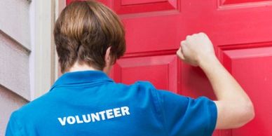 Volunteer knocking on a bright red door for outreach.