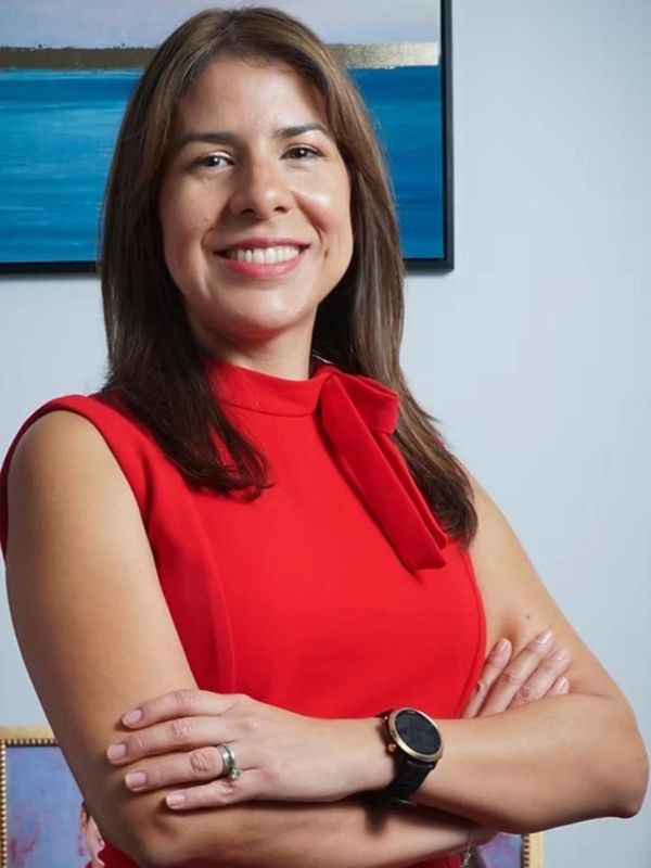Confident woman in a red dress smiling with arms crossed.
