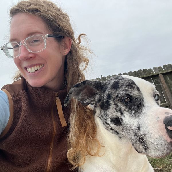 Woman smiling with her spotted dog outside.